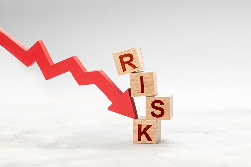 Red down arrow knocks down the cube RISK. Risky fall or investment concept.